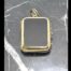 Main photo of locket displayed on top of some black marble with white line inclusions. The bail is to the top and the opening side is on the right. This locket can be worn with either the black onyx or bloodstone side on show.