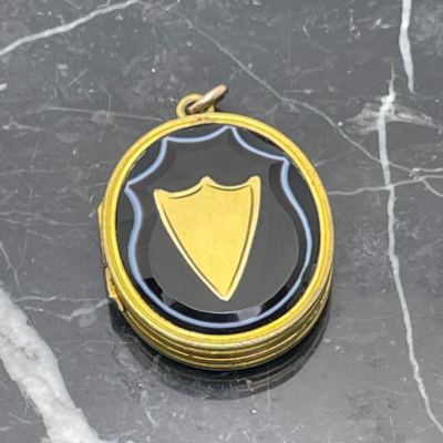 Main photo of locket seen displayed on a piece of black marble with white line inclusions.