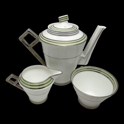 Photo of coffee pot, jug and sugar bowl only seen from a little height. The spouts of the pot and jug are facing right with the stylish silver handles on the left.
