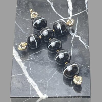 Photo of the cross lying on a block of black marble which also has white line inclusions. The cross has been photographed under a bright light.