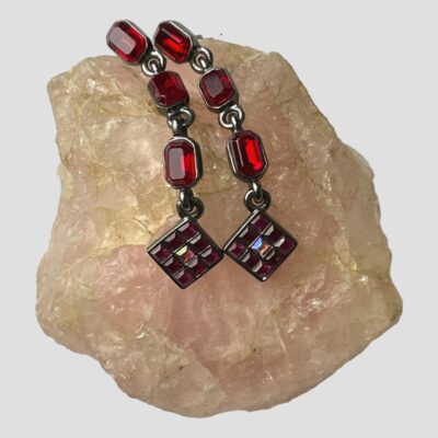 Photo of earrings displayed on top of a rock of rose quartz. The earring tops at top and the beautiful crystal squares hanging midway.