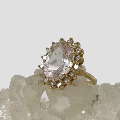 Photo of ring displayed on top of some quartz crystal with the ring front facing to the left. The ring is catching the light and all the stones are sparkling beautifully.