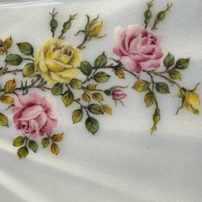 Close up photo of the enamelled back focusing on the beautiful yellow and pink roses.