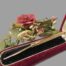Main photo of toothpick displayed fully extended and in the box. The box is a deep red velvet with a raised black velvet interior. The toothpick is fully extended and pick end is to the left.