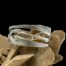 Main photo of cuff bracelet displayed on top of a large sand rose (formed desert sand) and shown with one of the cranes in full view at eye level and the beak of other visible. The bracelet is formed of 2 cut out crane figures placed completely mirrored one on left, one right and one upright one upside down and joined together. The centre of the bracelet is the heads with beaks joined together while the upper and lower bands are the cranes spread wings.