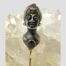 Main photo of pin leaning up against some quartz crystal with mostly just the head at the top of pin on show. The lady is facing straight at camera. The garnet cabochon necklace and amethyst to the top of her turban hat are visible as are the amethysts of her somewhat crazed looking eyes! The face and neck are silver and the turban hat and collar are in gilt.