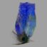 Main photo of vase seen from an eye level with one corner in the foreground and 2 sides on display. There is a single peacock feather at the front which pales in comparison to the beautiful cobalt blue of the vase.