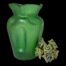 Main photo of vase seen from an eye level with one dimpled side in the foreground to the left. The vase is a striking slightly iridescent emerald green colour. There is a small posy of pale green coloured flowers on the righthand side of the vase.