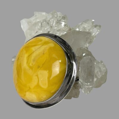 Secondary photo of brooch seen from a slight sideways angle with the brooch front facing left. The brooch is leaning up against some quartz crystal.
