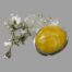 Main photo of brooch seen leaning up against a clump of quartz crystal with a sprig of white flowered orchids to the left. The size and colour of the amber is very vibrant.