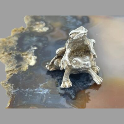 Photo of the frogs posed on top of a piece of agate with both facing slightly off camera.
