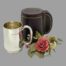 Main photo of christening displayed outside and to the left of its case which is closed. The handles for both the mug and case are on the right and there is a small posy of flowers including a red rose to the right of the mug and in front of the case.