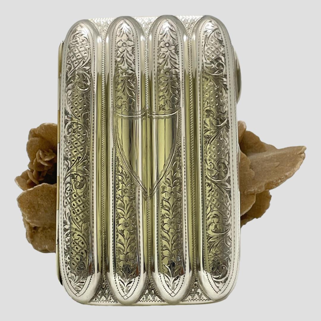 Main photo of cigar case shown closed and displayed upright against a rock of dessert sand rose. The shield cartouche side is on display.
