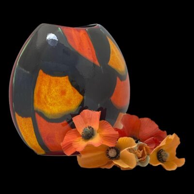 Photo of vase seen from a diagonal angle with the orange patch side facing towards the bottom right of the picture. The poppies that were previously inside the vase are now displayed in front of the vase.