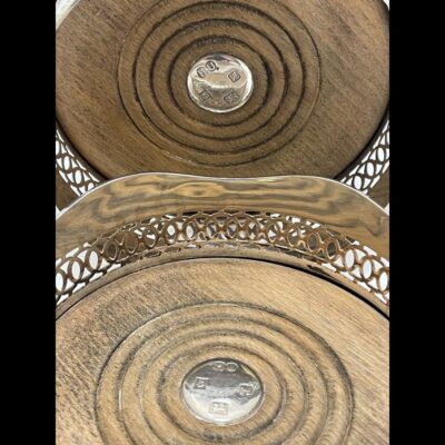 Close up photo of inside of the 2 coasters showing the wood with silver disc with hallmark to the centre of each.
