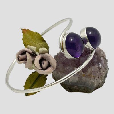 Secondary photo of the bracelet displayed with amethyst ends on top of a lump of natural amethyst and facing towards the right.