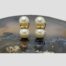 Main photo of the earrings displayed side by side on top of a slice of natural agate. Both the earrings are front facing. One pearl is above the other as in a figure of 8 with a gold band separating the 2.