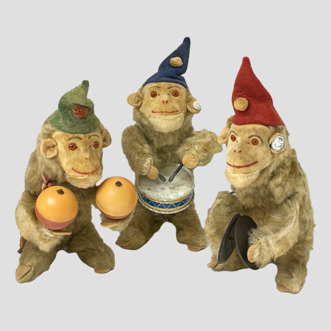 Main photo of the 3 monkeys posed in a row green hat maracas monkey on left, red hat cymbals monkey on the right and blue hat snare drum monkey in the centre and slightly back from other 2. They are a very cheerful troop of monkeys each with a happy smile of its face.