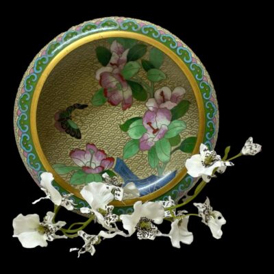 Main photo of bowl displayed in an upright position to show the interior decoration of peonies and butterfly. The bowl is set against a black background with a spray of small white orchid flowers in the foreground which enhances the colour of the bowl.