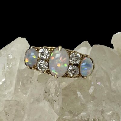 Main photo of ring displayed on top of some quartz crystal and seen with ring front forward facing. Quite a neutral colour palette on the opals at this angle and light but you can see the colours are there within.