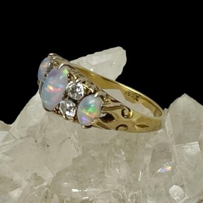 Photo of ring displayed on top of some quartz crystal and seen with ring front facing towards the left. There is a little more colour play with the ring at this angle. The 18ct hallmark is visible to the inside band.