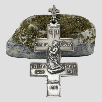 Main photo showing the Joan of Arc side of cross. It is leaning against a natural rock of lapis but the rock side. The Fleur de Lis bail is resting on the rock at the top.