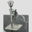 Main photo showing miniature with the lamp in the bottom left corner of shot. The piece is shown diagonally displayed with lamp in left foreground, ladder leaning against it with the lamplighter halfway up the ladder. The piece is displayed on top of black marble with white line inclusions.