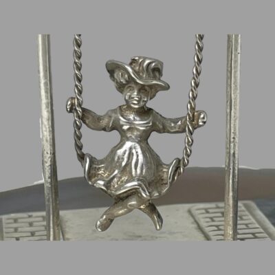 Close up photo of the girl on the swing. She has a big smile on her face and is dressed in an old style bonnet and dress.