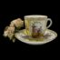 Main photo of cup on top of saucer seen from a near eye level. The handle is to the right. One Hand-painted panel with courting couple is on display to the centre of the cup (walking hand in hand) and 2 panels with courting couples are visible to left and right on the saucer. There is a small posy of pale pink roses to the left.