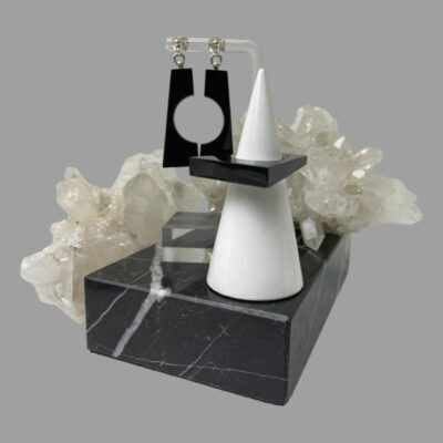 Main photo of ring on cone shaped stand with earrings hanging behind from a clear plastic stand slightly behind and to the left. Both stands are on top of some black marble and there is some quartz crystal behind the whole ensemble.