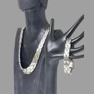 Photo of necklace and bracelet displayed off their dark display stands and seen from a side angle. The necklace is seen from a side angle with front facing towards left.