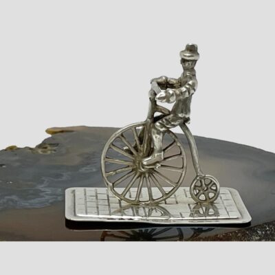 Main photo of penny farthing rider shown displayed on top of a slice of natural agate in profile facing towards the left.