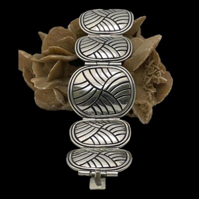 Secondary photo of bracelet laid across a rock of desert sand rose and seen straight on with one clasp end in the centre foreground. The largest panel is now leaning up against the side.