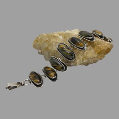 Main photo of the bracelet shown undone and laid across a rock of natural quartz crystal of a sandy colour. The bracelet is laid at an angle horizontally with the closing clasp end to the left.