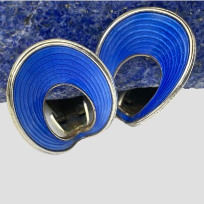 Photo of earrings shown in close up with one on left slightly overlapping the other. The earrings are still displayed in front of the blue lapis stone.