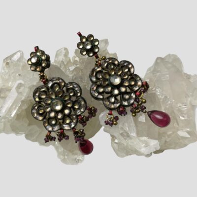 Secondary photo of both earrings displayed on top of a rock of natural quartz crystal. The earrings are laid diagonally across with the top ends in the top left corner and the pink drops towards the bottom right.