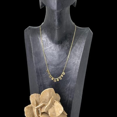 Main photo of necklace displayed on a dark wood display stand set against a black background. A small rock of desert sand rose is visible in the foreground at the base of the display stand.
