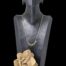 Main photo of necklace displayed on a dark wood display stand set against a black background. A small rock of desert sand rose is visible in the foreground at the base of the display stand.
