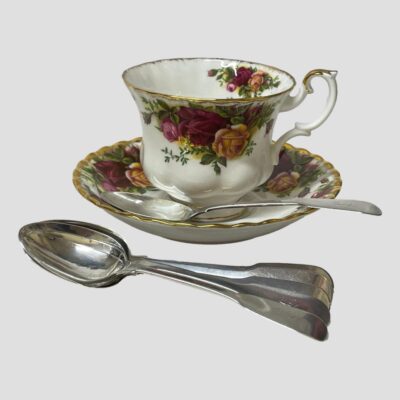 Main photo of 5 of the 6 teaspoons stacked on top of each other and placed in front of a cup and saucer. The 6th spoon is situated on the saucer and in front of the tea cup.