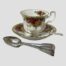 Main photo of 5 of the 6 teaspoons stacked on top of each other and placed in front of a cup and saucer. The 6th spoon is situated on the saucer and in front of the tea cup.