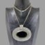 Main photo of necklace displayed on a dark wooden display stand and seen with the pendant front forward facing. The chain has had to be doubled up as it is quite long so the clasp is visible at the centre of the neck. The pendant is immense and is almost as wide as the display stand. If you are after a statement piece like no other, this has to be the one!