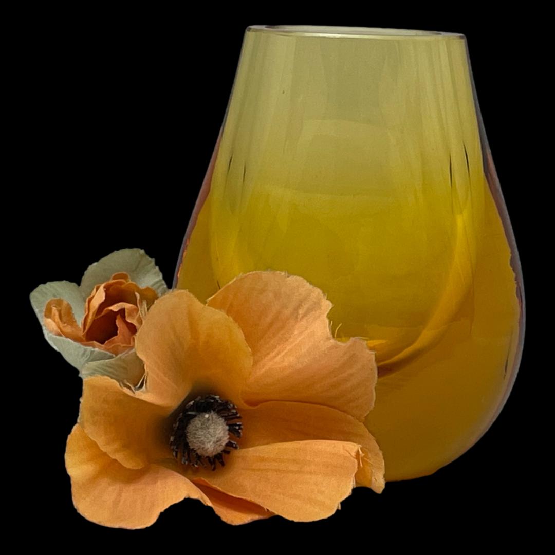 Main photo of vase seen with widest angle on show. Hambone shape is like a U shape which narrows at the top. The vase has a thick base giving it the hefty weight and solid stature. Lovely amber colour against a black background enhances the warmth of the colour. There is a small orange coloured poppy and bud to the bottom left of the vase.