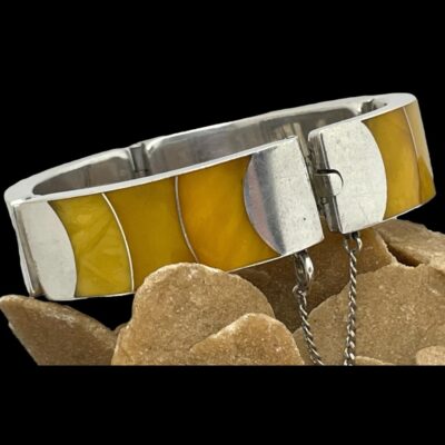 Close up photo of the bracelet seen with one panel in the left foreground. The clasp area is to the right and the bracelet is set at an angle on top of some desert sand rose.