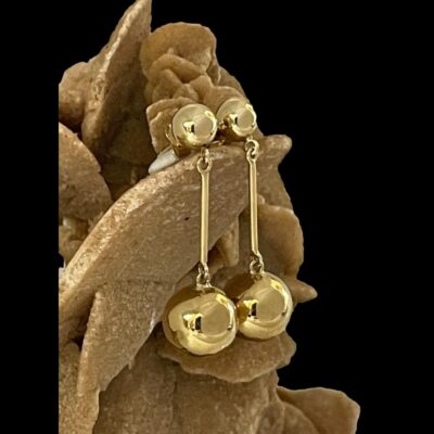 Photo of the earrings displayed vertically hanging from a rock of desert sand rose and shown from a slight side view.