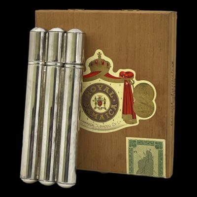 Main photo of the cigar case leaning up against an old wooden Jamaican cigar box. The lid end is at the top. The case is for larger cigars and has 3 tubes moulded together with a removable lid (not hinged) which is also moulded to cigar shape. There is nothing fancy about this item, no scrollwork or decorations of any kind - just plain silver plate.