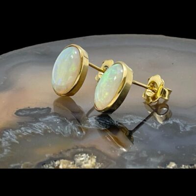 Photo of earrings still displayed on top of a slice of natural agate with the earring fronts facing to the left. The posts and butterflies are visible.