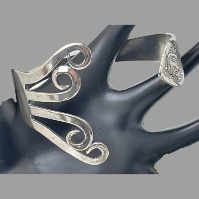 Close up photo of the bracelet whilst still displayed on the black display stand. The curled up prong end on the left and pointed handle end on right.