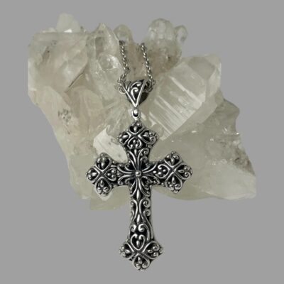 Main photo of cross shown leaning in front of a rock of quartz crystal with the pierced work side on show.