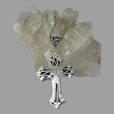 Photo of cross shown leaning against a rock of quartz crystal and showing the smoother reverse side. The 925 is just visible to the centre.