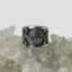 Main photo of ring displayed on top of a rock of natural quartz crystal with the ring front forward facing. The large swirl is to the centre with 2 small swirls coming off it to either side. There are 4 dots spread out top left and right and bottom left and right of large swirl. There is a band of plain silver to the top and bottom edge of the ring.